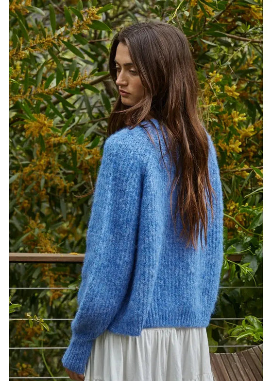 Woman wearing a blue sweater with a green foliage background