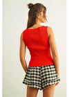 Woman wearing a red sleeveless top and checkered skirt on a plain background