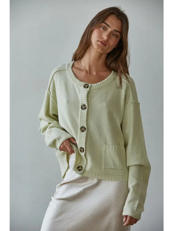 Woman wearing a light green cardigan against a plain background