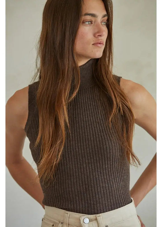 Woman wearing a brown ribbed tank top against a neutral background
