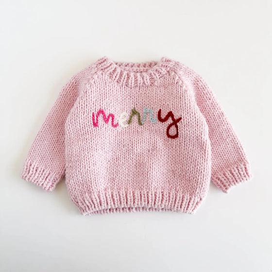 Pink knitted sweater with colorful letters on a white background