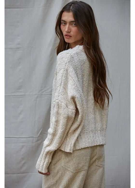Woman wearing a textured beige sweater and pants against a plain background