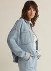 Woman wearing a light blue denim outfit on a beige background