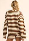 A woman shown from behind wearing a brown and cream striped knit long-sleeve top and matching shorts against a plain light beige studio background.