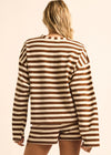 A woman shown from behind wearing a brown and cream striped knit long-sleeve top and matching shorts against a plain light beige studio background.