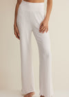 White ribbed lounge pants worn by a person on a beige background