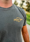 Person wearing a gray t-shirt with yellow text outdoors