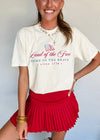 Woman wearing a white t-shirt with patriotic text and a red pleated skirt against a light background