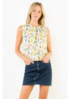 Woman wearing a sleeveless floral top and denim skirt on a white background