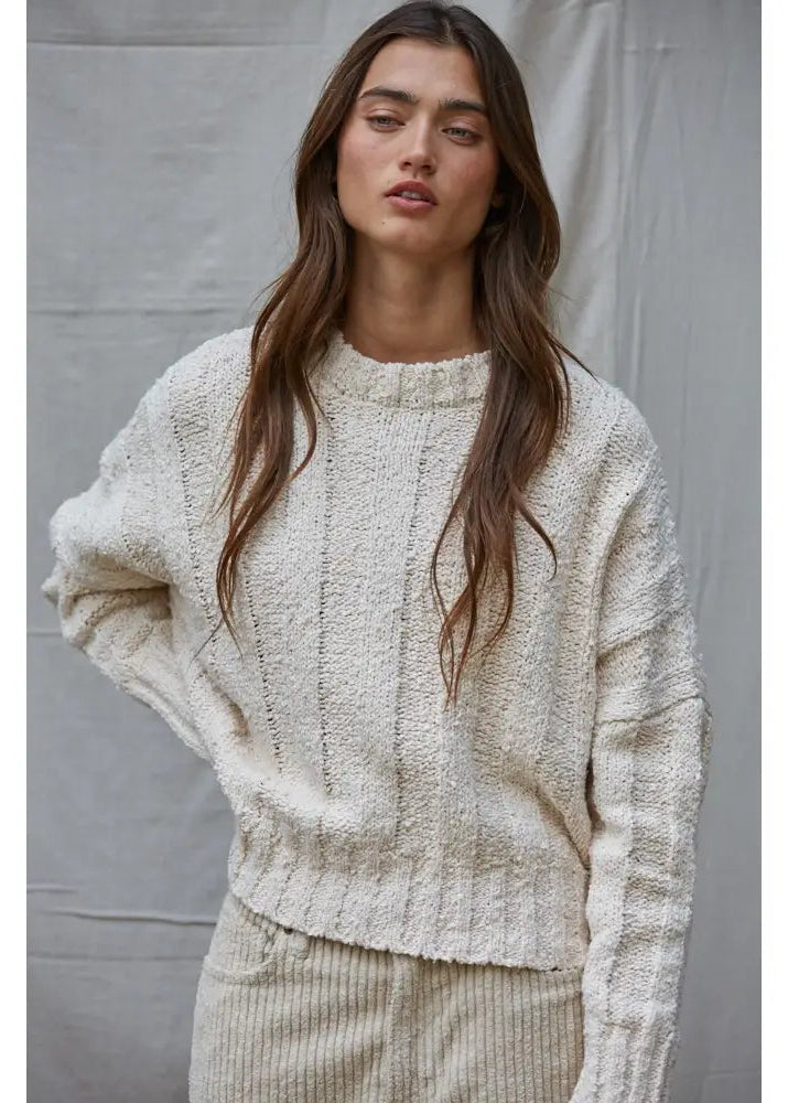  Woman wearing a cream knitted sweater against a plain background
