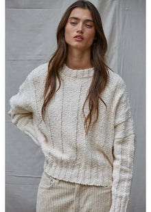  Woman wearing a cream knitted sweater against a plain background