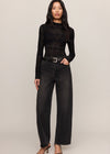 Woman wearing a black long-sleeve top and black jeans on a plain background