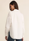 Person wearing a white shirt and blue jeans on a beige background