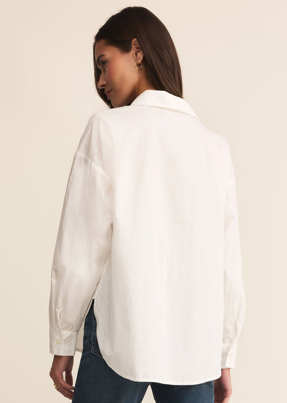 Person wearing a white shirt and blue jeans on a beige background