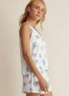 Woman wearing a white sleeveless top with blue floral patterns on a beige background