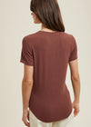 Woman wearing a brown t-shirt against a beige background