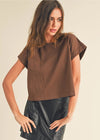 Woman wearing a brown top and black leather skirt on a beige background