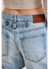 Close-up of a person wearing light blue jeans with a brown leather patch on the back pocket.