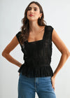 Woman wearing a black sleeveless top and blue jeans on a white background