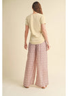 Woman wearing a light-colored top and patterned pants on a beige background