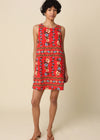 Woman wearing a red floral dress against a beige background