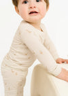 Baby wearing a long-sleeve cream shirt with small patterns on a white background
