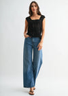 Woman wearing a black top and blue jeans on a white background