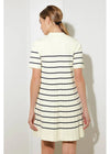 Woman wearing a white dress with black stripes against a plain background