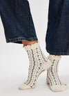 White socks with black speckles worn with blue jeans on a white background