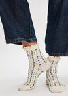 White socks with black speckles worn with blue jeans on a white background