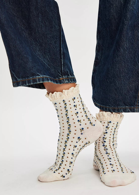 White socks with black speckles worn with blue jeans on a white background