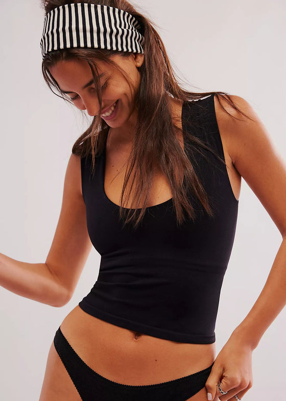Woman wearing a black tank top and black bikini bottom with a white background