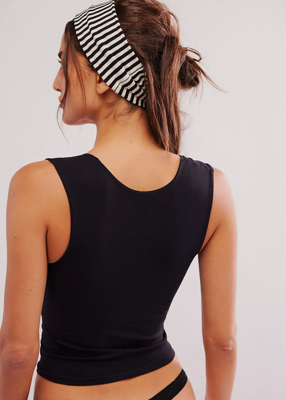 Woman wearing a black tank top and striped headband on a plain background