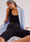 Woman wearing black athletic outfit with a light blue jacket draped over her shoulders.