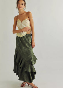  Woman wearing a green ruffled skirt and yellow top on a plain background