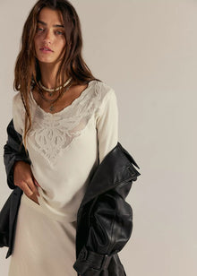  Woman wearing a black leather jacket over a white dress with lace details on a plain background