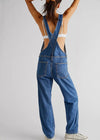 Person wearing blue denim overalls on a plain background