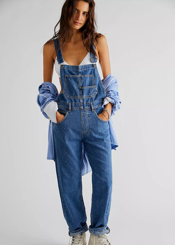 Person wearing denim overalls with a plain background