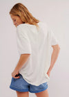 Person wearing a white oversized t-shirt and blue shorts on a plain background