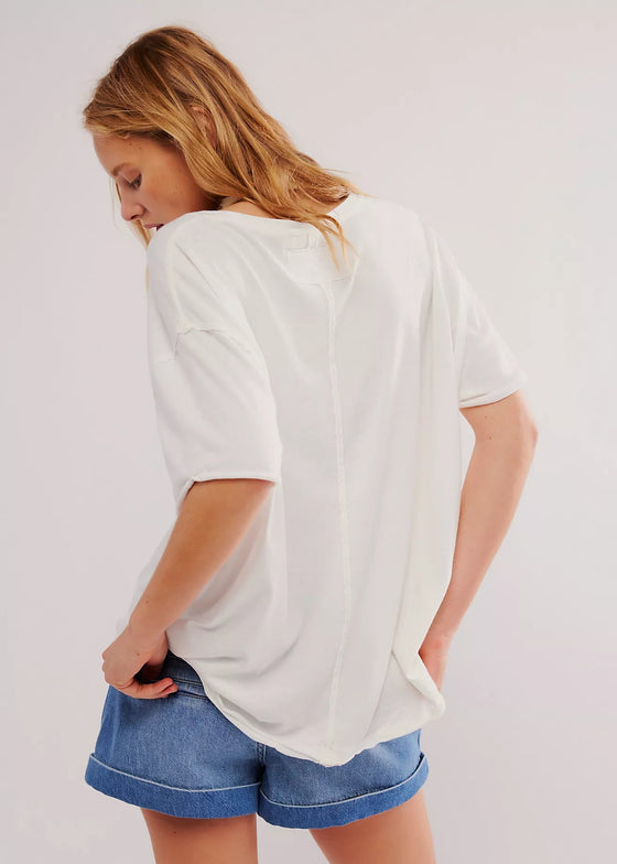 Person wearing a white oversized t-shirt and blue shorts on a plain background
