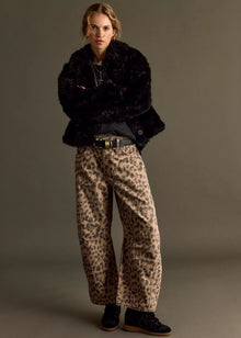  Person wearing a black fur coat and leopard print pants against a gray background