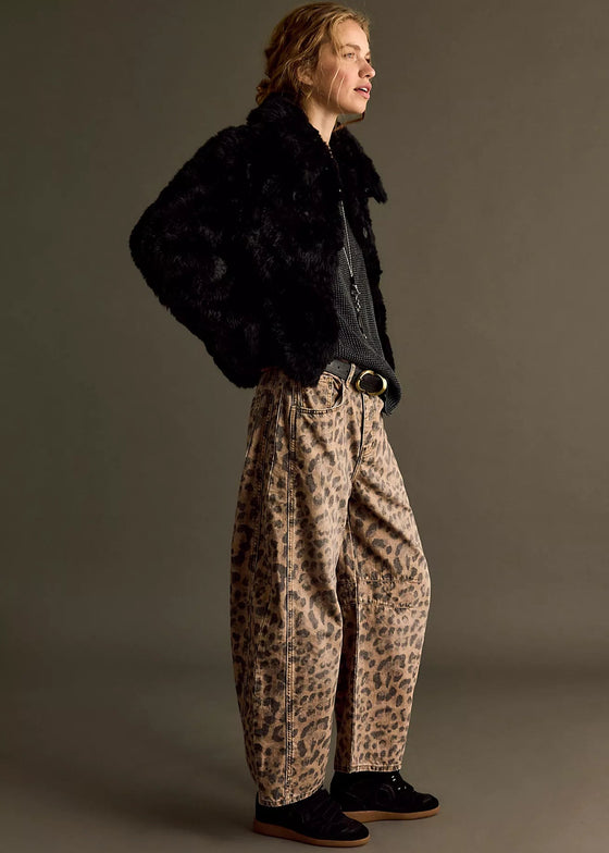 Person wearing a black fur coat, dark shirt, and leopard print pants on a gray background