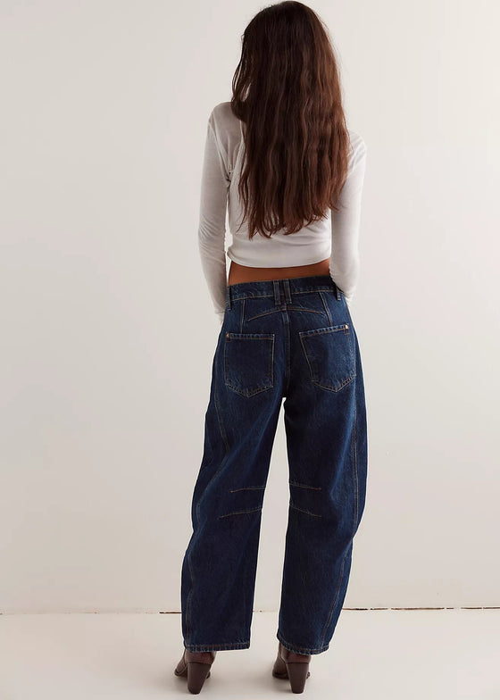 Person wearing a white long-sleeve top and dark blue jeans against a white background