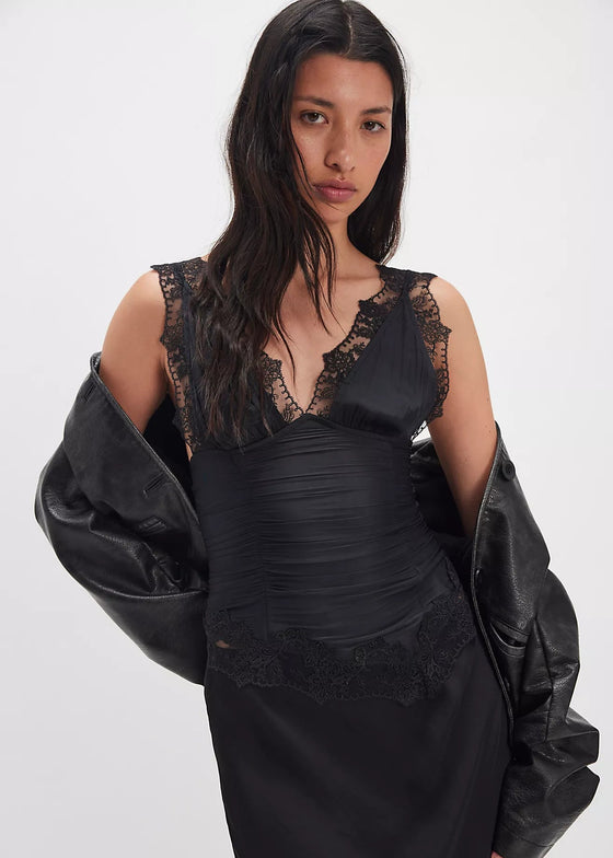 Woman wearing a black dress with lace details and a black jacket on a white background