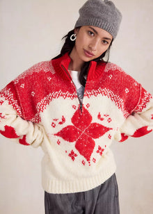  Person wearing a red and white patterned sweater with a gray knit hat on a plain background