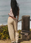 Person standing by a wooden post with a cooler box on a beach