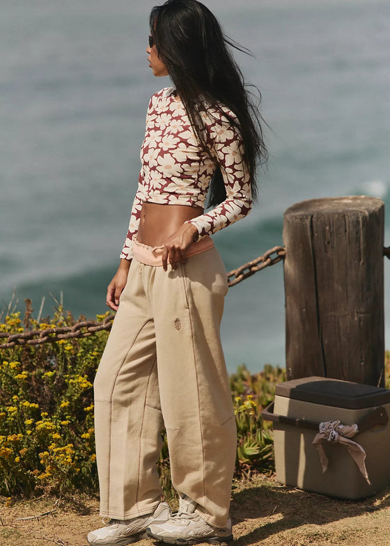 Woman standing by a wooden post with a scenic ocean view in the background