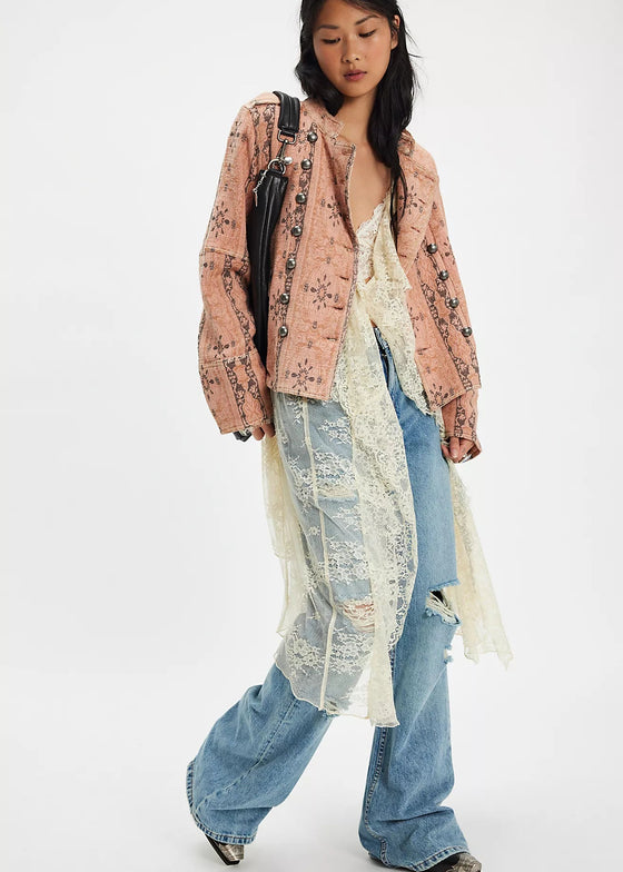 Person wearing a floral jacket, sheer top, and jeans on a white background