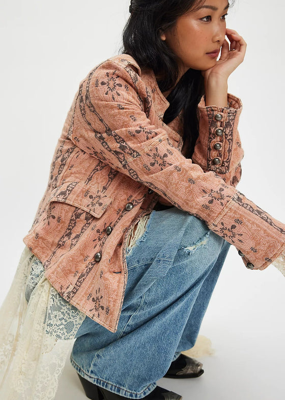 Woman wearing a patterned pink jacket and blue jeans on a white background