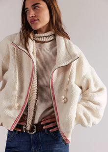  Woman wearing a cream-colored jacket with red trim on a plain background